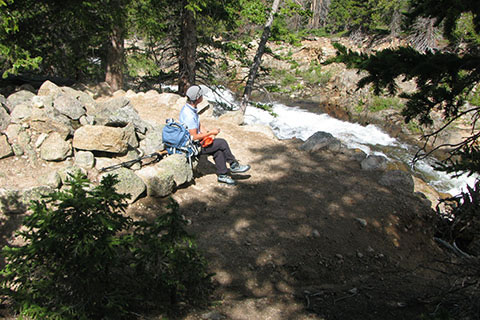 hiker resting at switchback overlooking the Roaring River