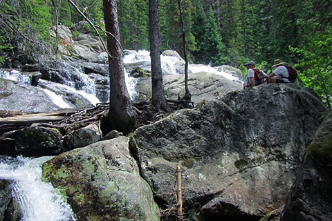 Cascade Falls from below, hikers sitting on a rock